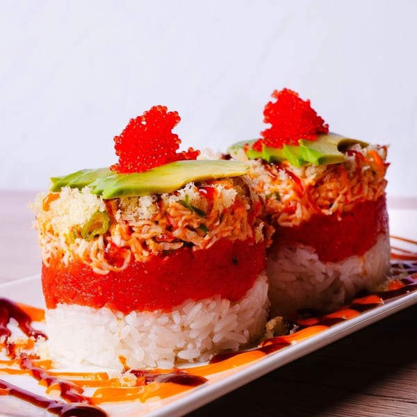 Two Hornbill Sushi & Asian Fusion tuna towers with avocado, roe, and sauce on a white plate.