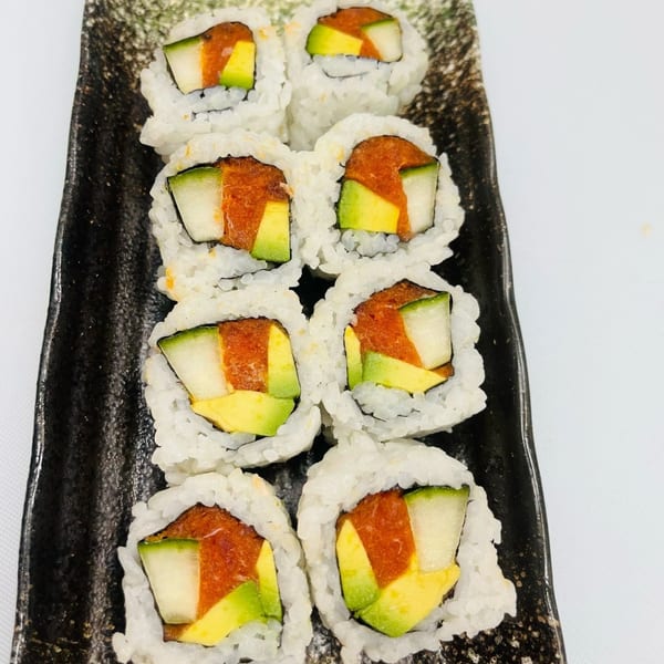 Eight Hornbill Sushi rolls with avocado, cucumber, and spicy tuna on a black rectangular plate.