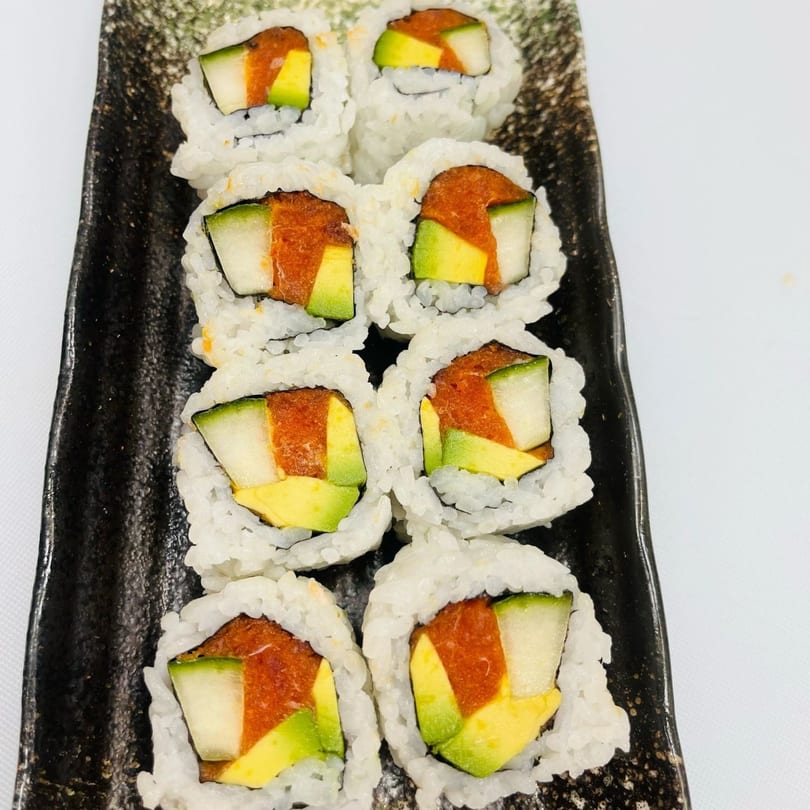Eight Hornbill Sushi rolls with avocado, cucumber, and spicy tuna on a black rectangular plate.