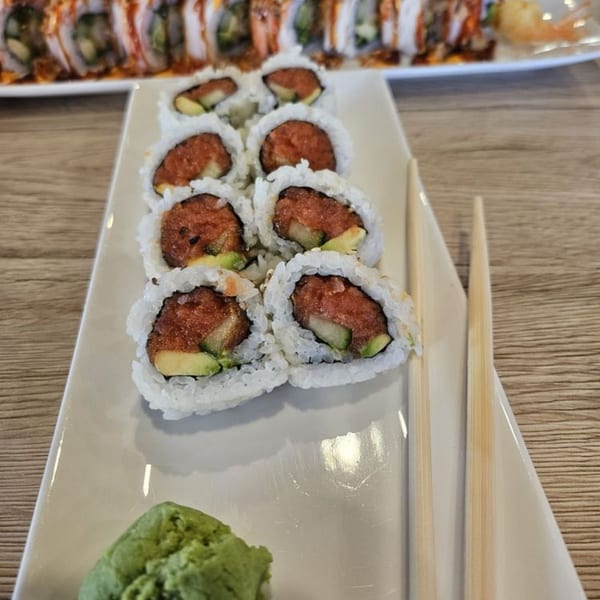 Hornbill Sushi's spicy tuna and avocado sushi rolls with wasabi and chopsticks on a white plate.