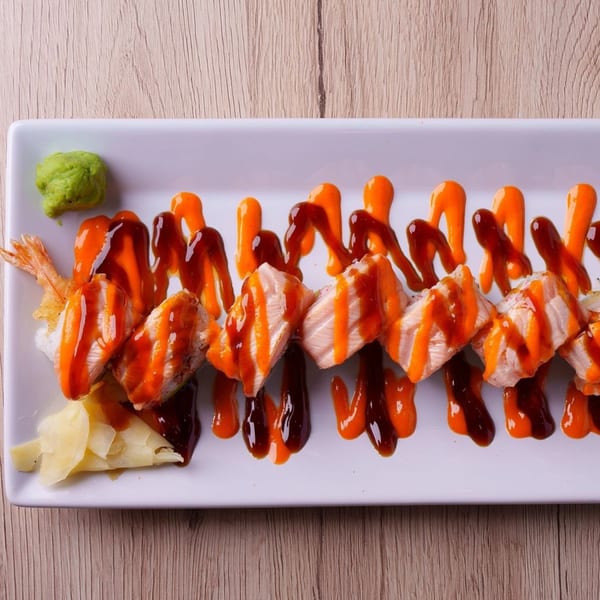 Hornbill Sushi's salmon and shrimp tempura rolls drizzled with orange and brown sauces, with wasabi and ginger.