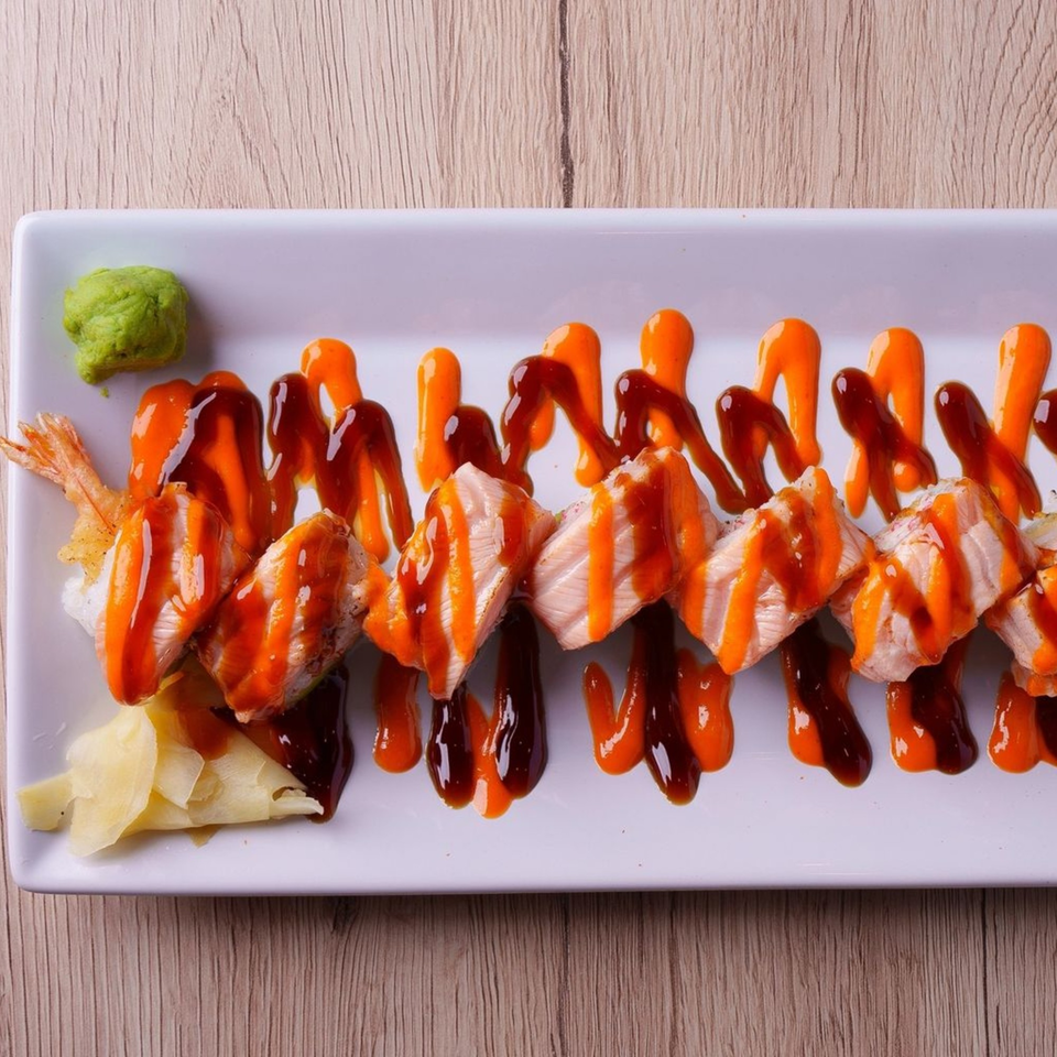 Hornbill Sushi's salmon and shrimp tempura rolls drizzled with orange and brown sauces, with wasabi and ginger.