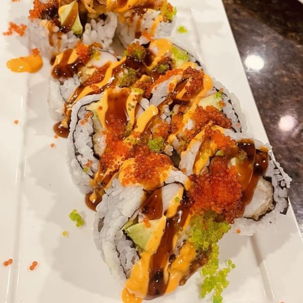 Hornbill Sushi & Asian Fusion's sushi rolls with orange and green roe, drizzled with sauces.