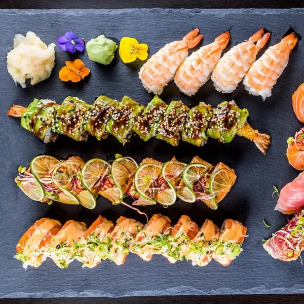 Assortment of Hornbill Sushi & Asian Fusion rolls, nigiri, and sashimi with ginger, wasabi, and edible flowers.