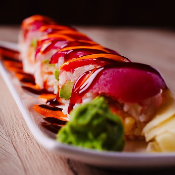 Hornbill Sushi & Asian Fusion's vibrant sushi roll with tuna, avocado, and colorful sauces on a white plate.