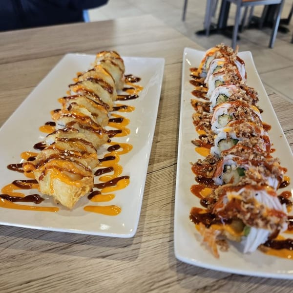 Two plates of Hornbill Sushi & Asian Fusion rolls, one fried, both drizzled with sauces.