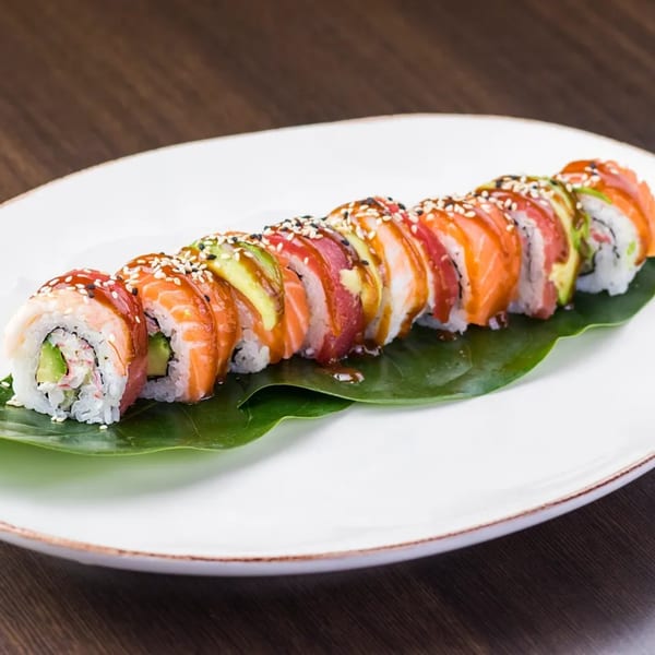Hornbill Sushi & Asian Fusion's colorful sushi roll with salmon, tuna, and avocado on a white plate.