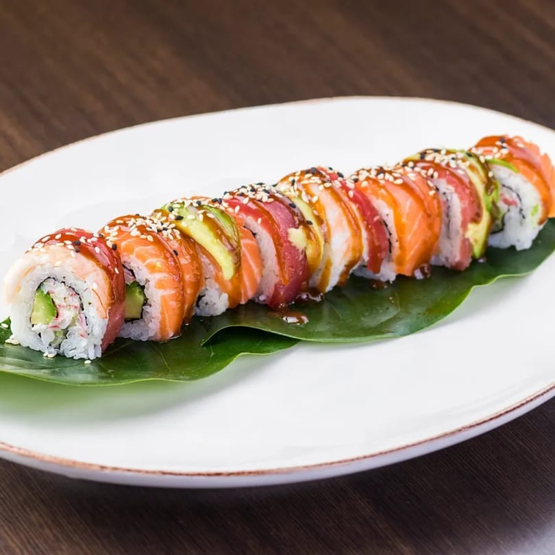 Hornbill Sushi & Asian Fusion's colorful sushi roll with salmon, tuna, and avocado on a white plate.