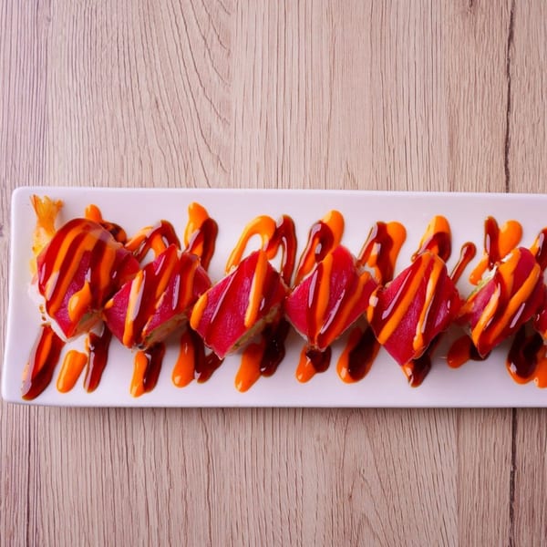 Hornbill Sushi & Asian Fusion's sushi roll with red tuna, orange, and dark sauces on a white plate.