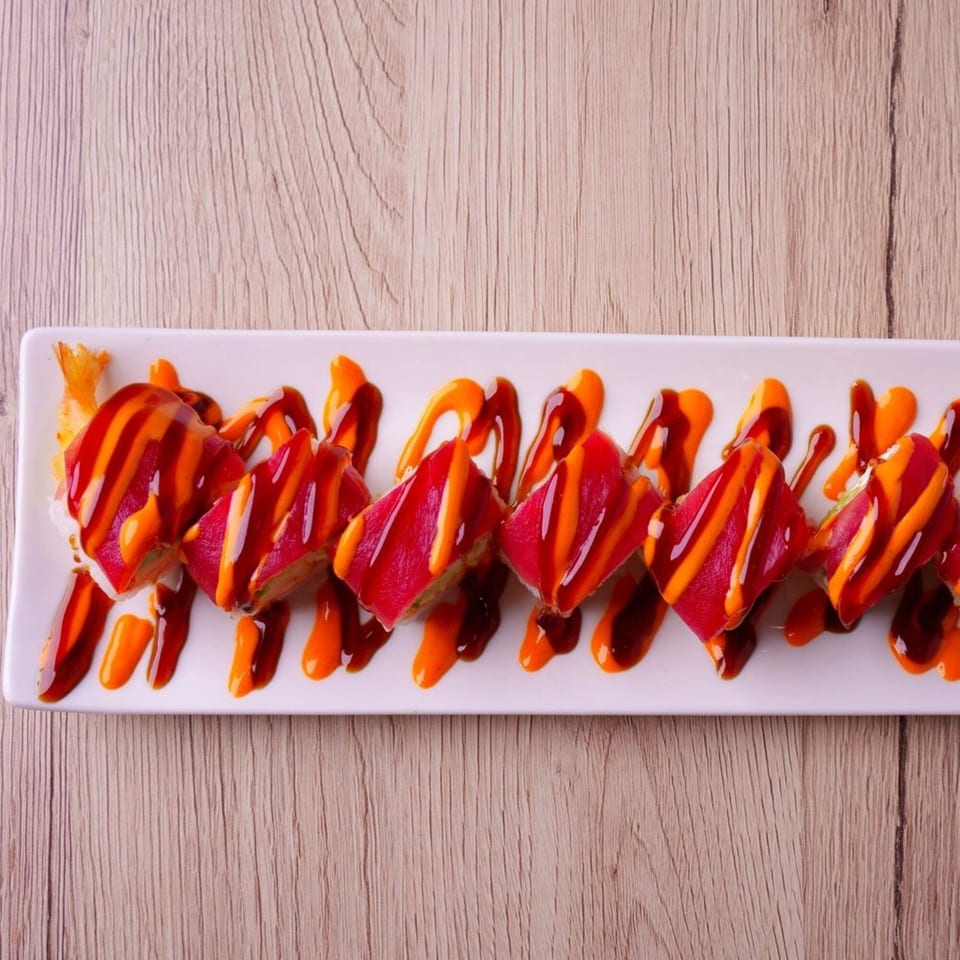 Hornbill Sushi & Asian Fusion's sushi roll with red tuna, orange, and dark sauces on a white plate.